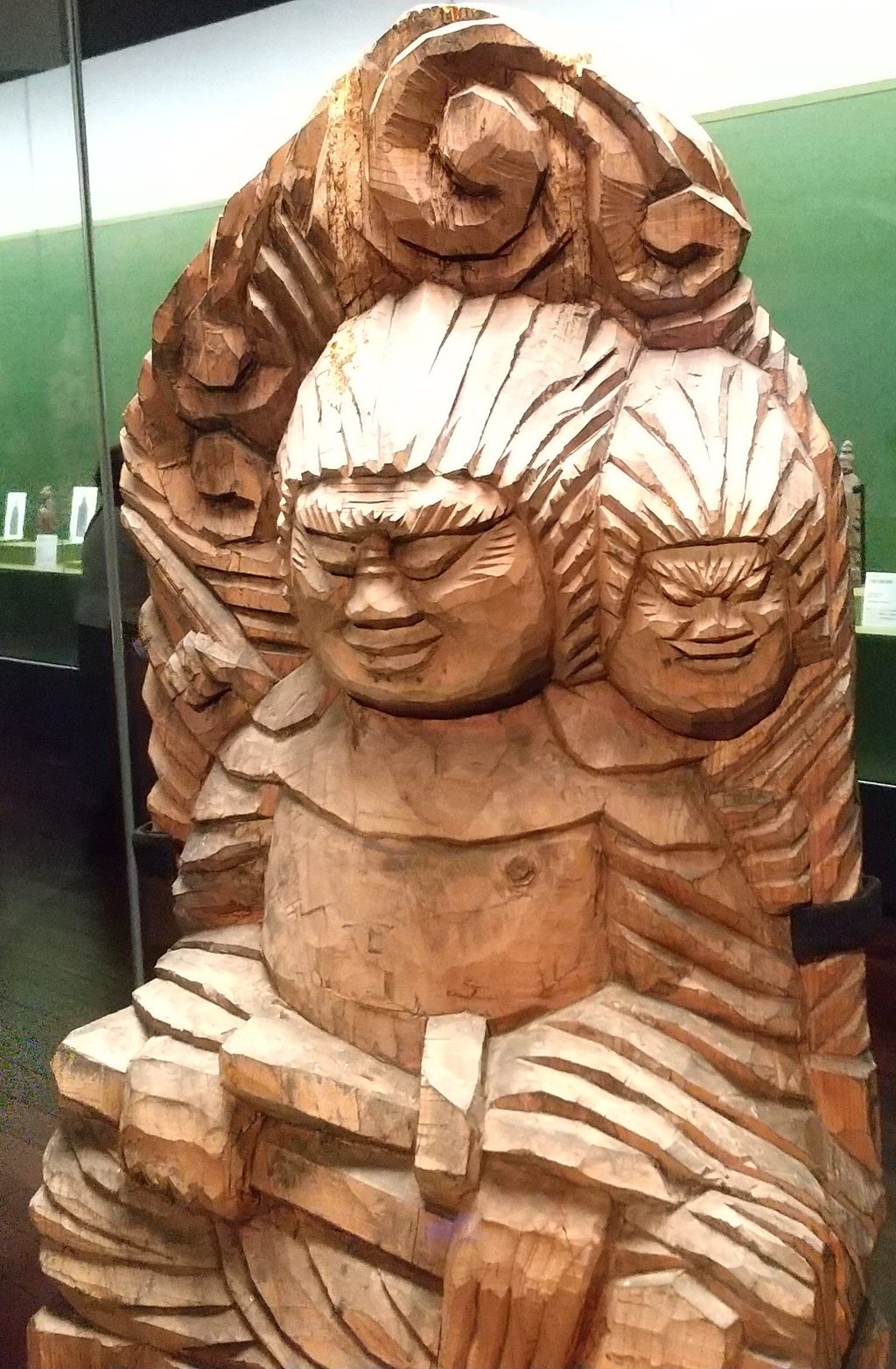 二つの顔を左右に並べ、鉞と雲形光背を備えた円空作の木造両面宿儺坐像